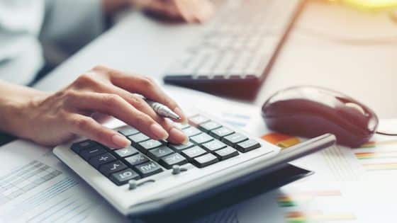 Comment faire une note de frais - une femme tapant sur une calculatrice à son bureau