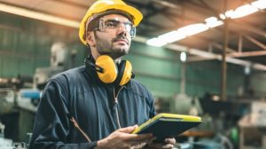 gestion des demandes d intervention - un technicien de maintenance avec un casque de chantier, et des protections visuelles et auditives dans un atelier