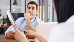 comment convaincre un client - un homme à l'allure sceptique écoutant une femme présentant des arguments