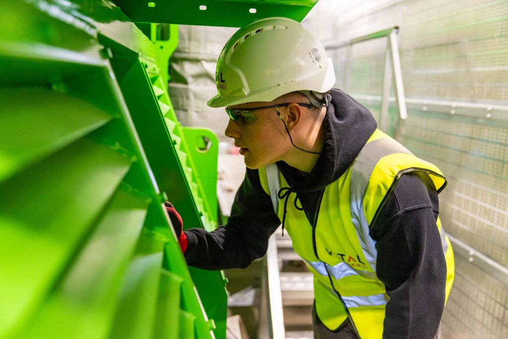 Technicien en gilet et casque de sécurité inspectant une machine industrielle lors d une opération de maintenance